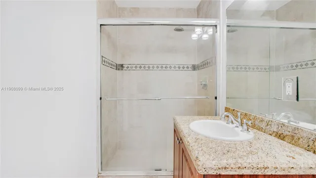 a bathroom with a granite countertop shower and a sink