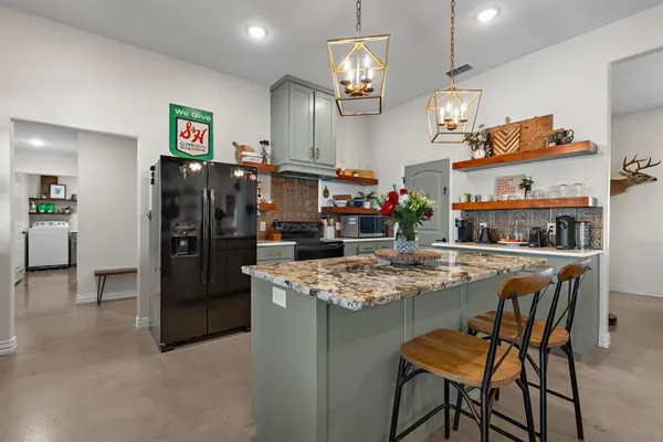 a kitchen area with stainless steel appliances kitchen island granite countertop a table and chairs in it