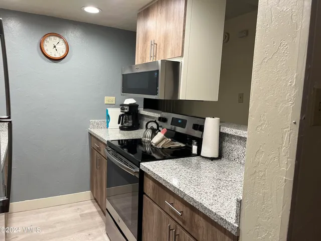 a kitchen with a sink and a stove with wooden floor