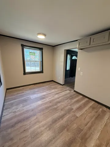 a view of an empty room with wooden floor and closet