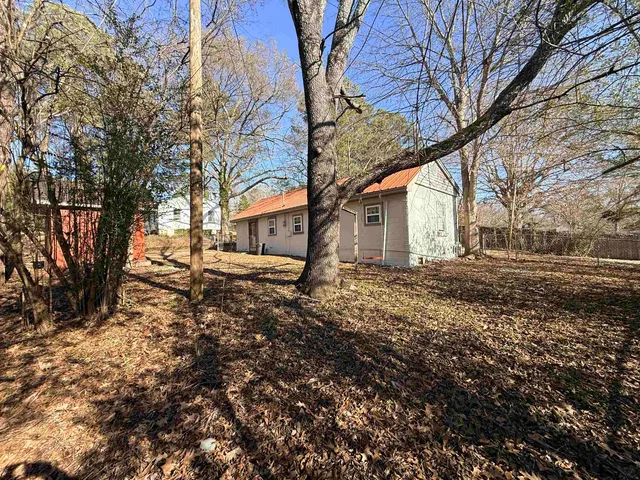a backyard of a house with large trees and outdoor seating