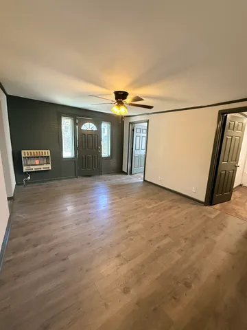 a view of a hallway with wooden floor and a living room