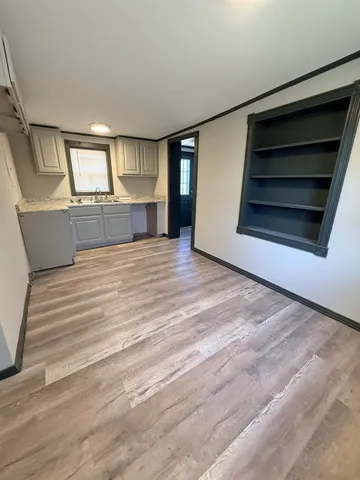 a view of kitchen and empty room with wooden floor