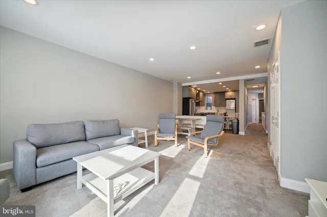 a living room with furniture and view of kitchen
