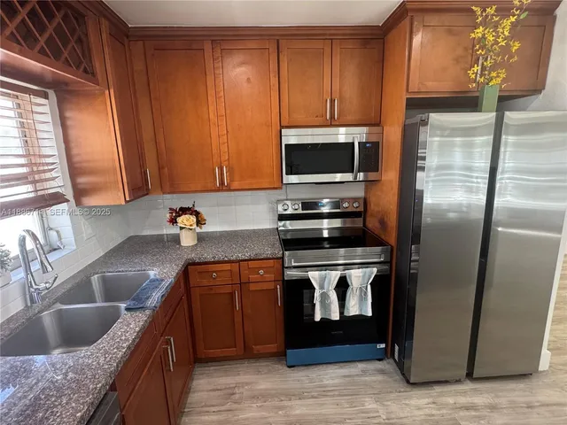 a kitchen with stainless steel appliances granite countertop a sink stove and refrigerator