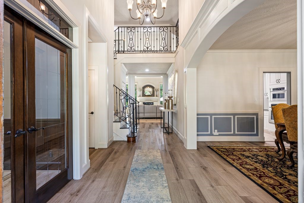 27722 Tiverton Court Spring, TX 77386 - Photo 4 of 33 The expansive hallway unfolds beneath soaring double-height ceilings, creating an immediate sense of openness and grandeur. Natural light pours in, guiding you toward the heart of the home while emphasizing its remarkable scale.