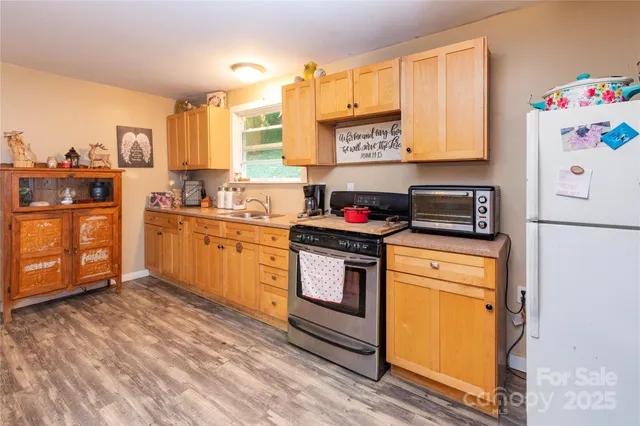 a kitchen with stainless steel appliances granite countertop a stove a sink dishwasher and a refrigerator with wooden floor