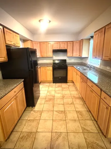 a large kitchen with granite countertop a refrigerator and a stove top oven