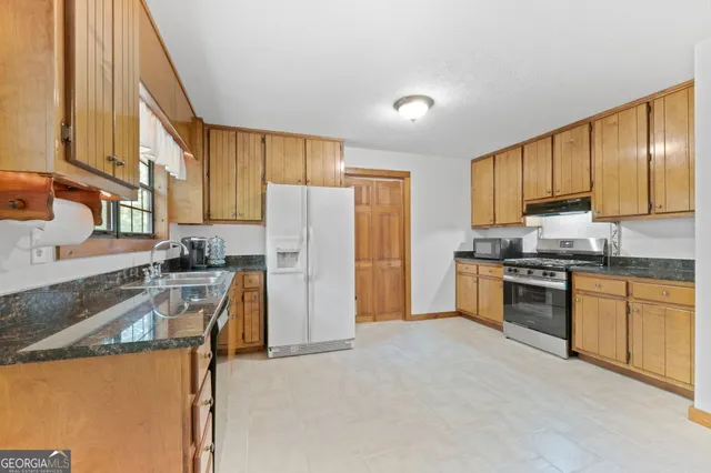 a kitchen with granite countertop a refrigerator stove top oven and sink