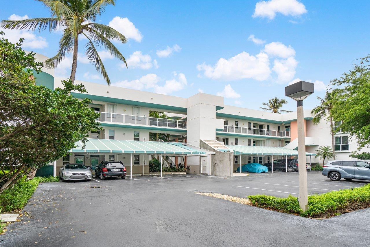 a front view of a building with parking space and palm trees
