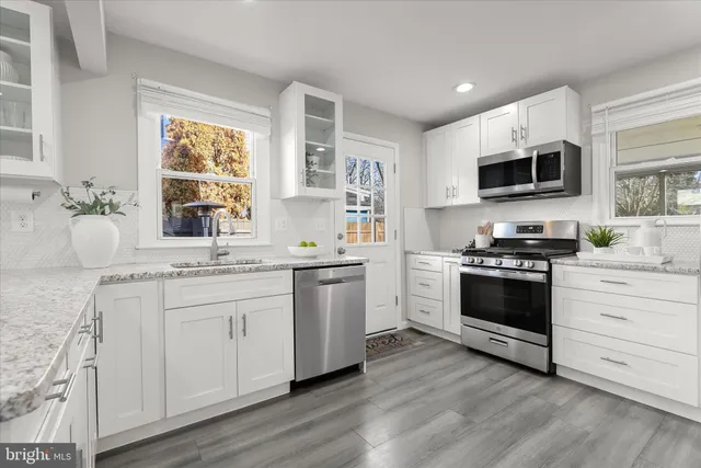 a kitchen with granite countertop a sink cabinets and stainless steel appliances