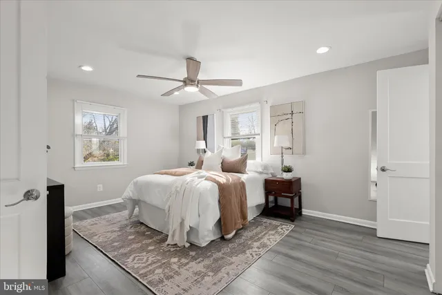 a spacious bedroom with a bed a dresser and wooden floor