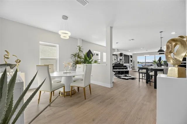 a kitchen with stainless steel appliances kitchen island granite countertop a refrigerator a stove a sink a dining table and chairs with wooden floor