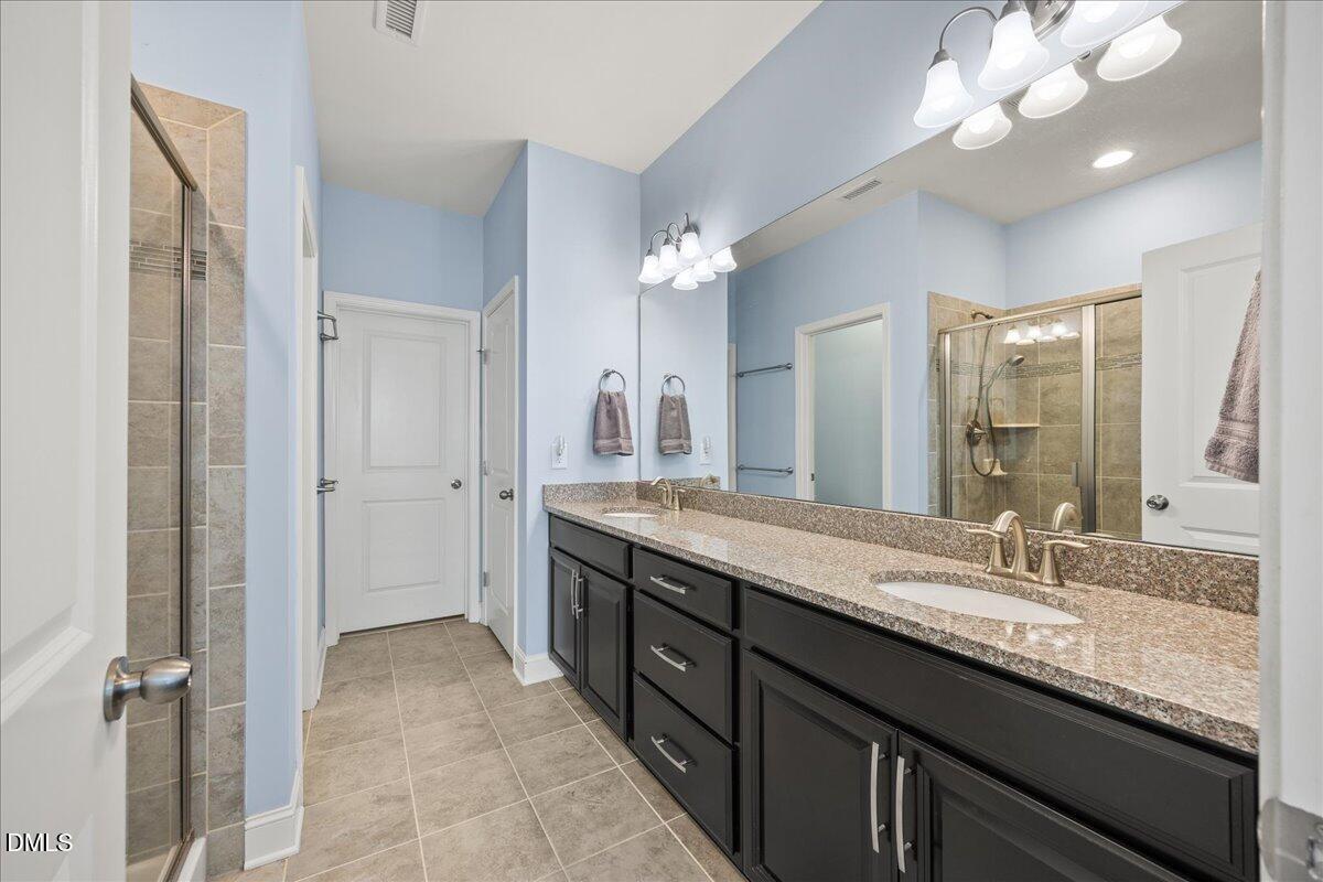 216 Mayfield Drive Apex, NC 27539 - Photo 25 of 66 a bathroom with a granite countertop sink a large mirror and a shower