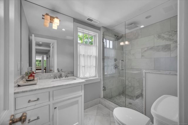 a bathroom with a granite countertop sink toilet a mirror and shower