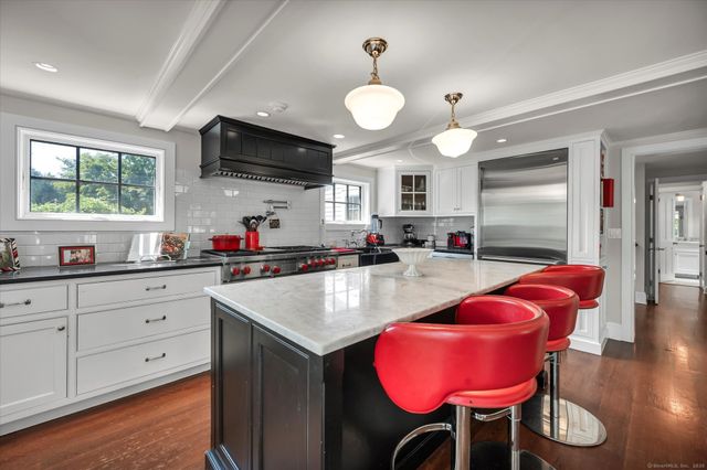 a kitchen with granite countertop a stove a sink and a refrigerator