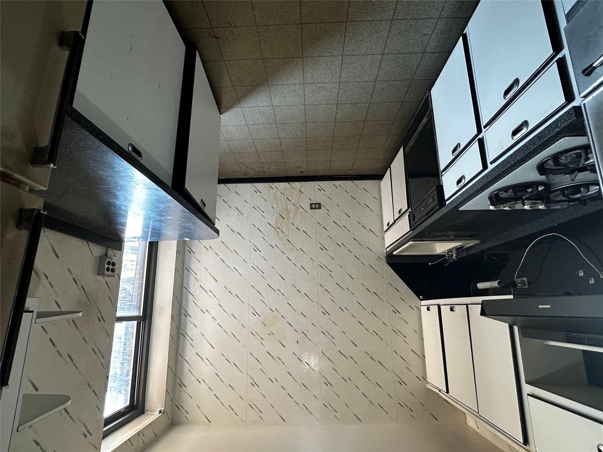 18-75 Corporal Kennedy Street, Unit 4A Queens, NY 11360 - Photo 9 of 25 Kitchen featuring cooktop, dark countertops, dishwasher, white cabinets, and range hood