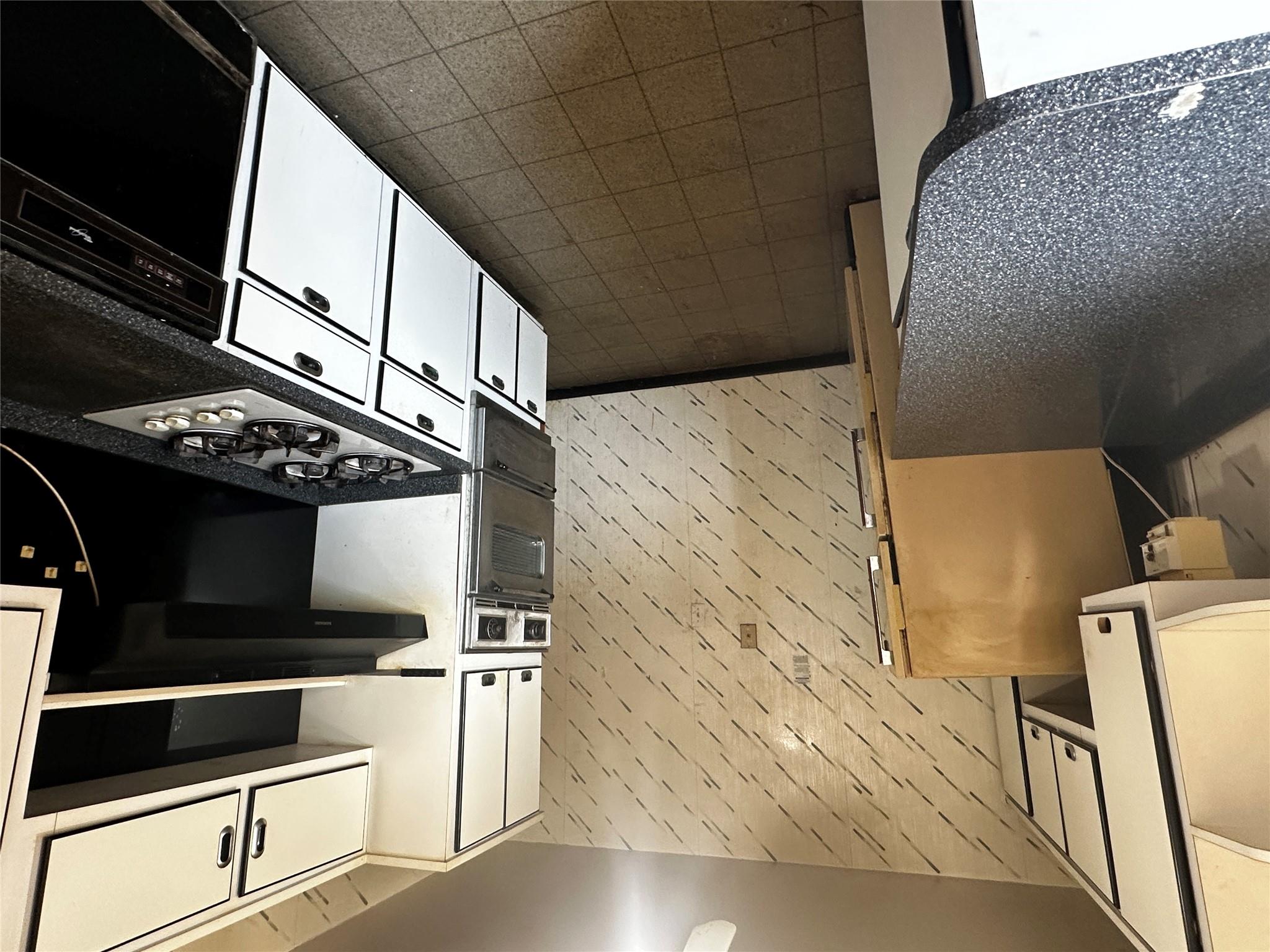 18-75 Corporal Kennedy Street, Unit 4A Queens, NY 11360 - Photo 10 of 25 Kitchen featuring wall oven, dark countertops, stovetop, white cabinetry, and a warming drawer
