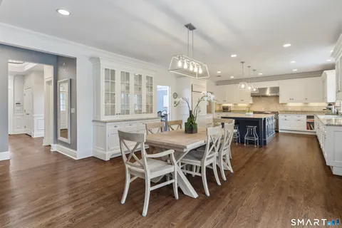 a kitchen with granite countertop a stove a sink dishwasher a dining table and chairs with wooden floor