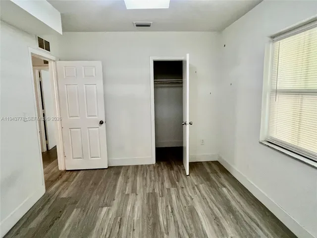 an empty room with wooden floor and a window