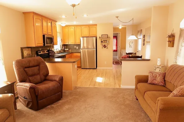 a living room with furniture kitchen view and a large window
