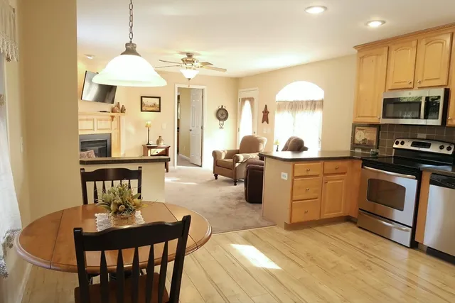 a kitchen with stainless steel appliances kitchen island granite countertop a stove a sink a dining table and chairs with wooden floor