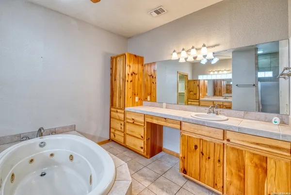 a spacious bathroom with a tub sink and mirror
