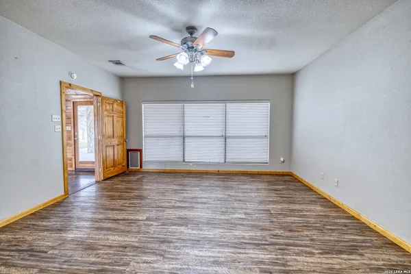 a view of an empty room with a window and wooden floor