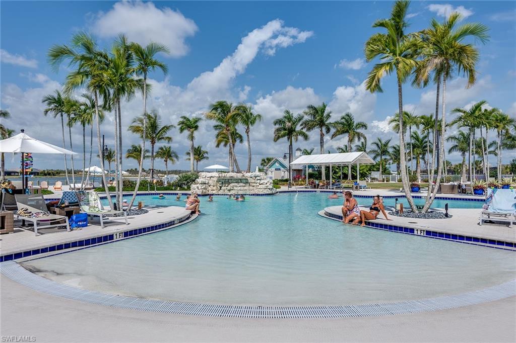 14685 Kelson Circle Naples, FL 34114 - Photo 39 of 50 a view of a swimming pool with a lawn chairs under palm trees