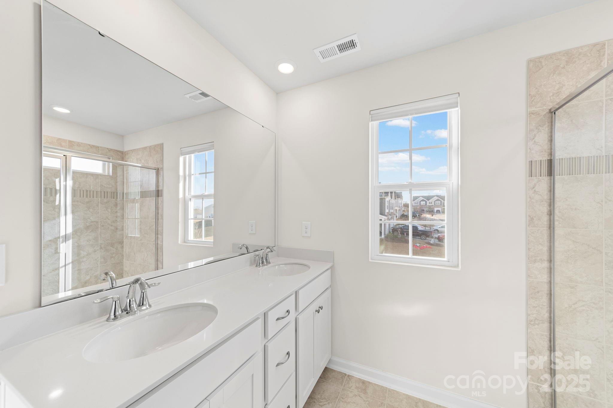5044 Moss Pine Way Tega Cay, SC 29708 - Photo 25 of 40 a bathroom with double vanity sink a mirror and a shower