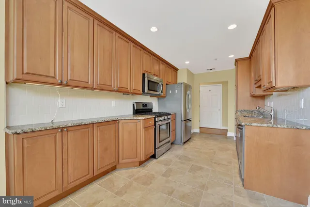 a kitchen with stainless steel appliances granite countertop a stove a sink and a refrigerator