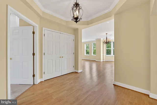 a view of a hallway with wooden floor and chandelier