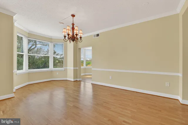a view of a room with wooden floor large windows and a chandelier