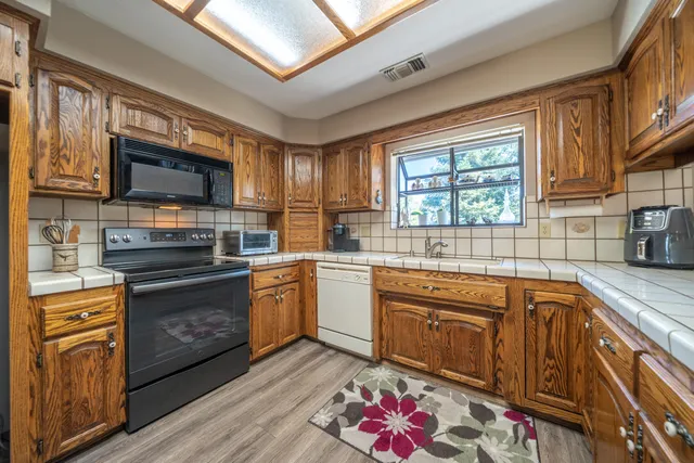 a kitchen with stainless steel appliances granite countertop a stove sink microwave and window