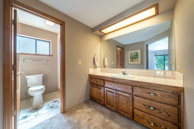 a bathroom with a granite countertop toilet sink and a mirror