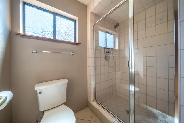 a white toilet sitting next to a bathroom next to a window