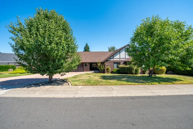 a view of a house with a yard and large trees