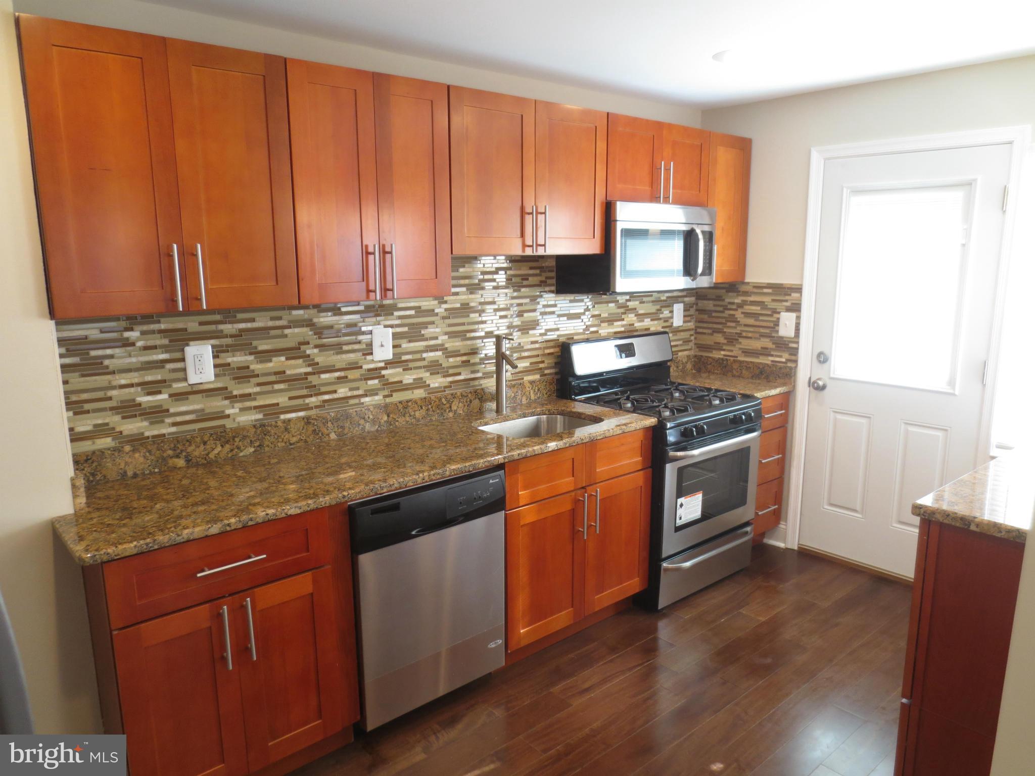 1801 Heathfield Road Baltimore, MD 21239 - Photo 2 of 28 a kitchen with stainless steel appliances granite countertop wooden cabinets a stove a sink and dishwasher with wooden floor