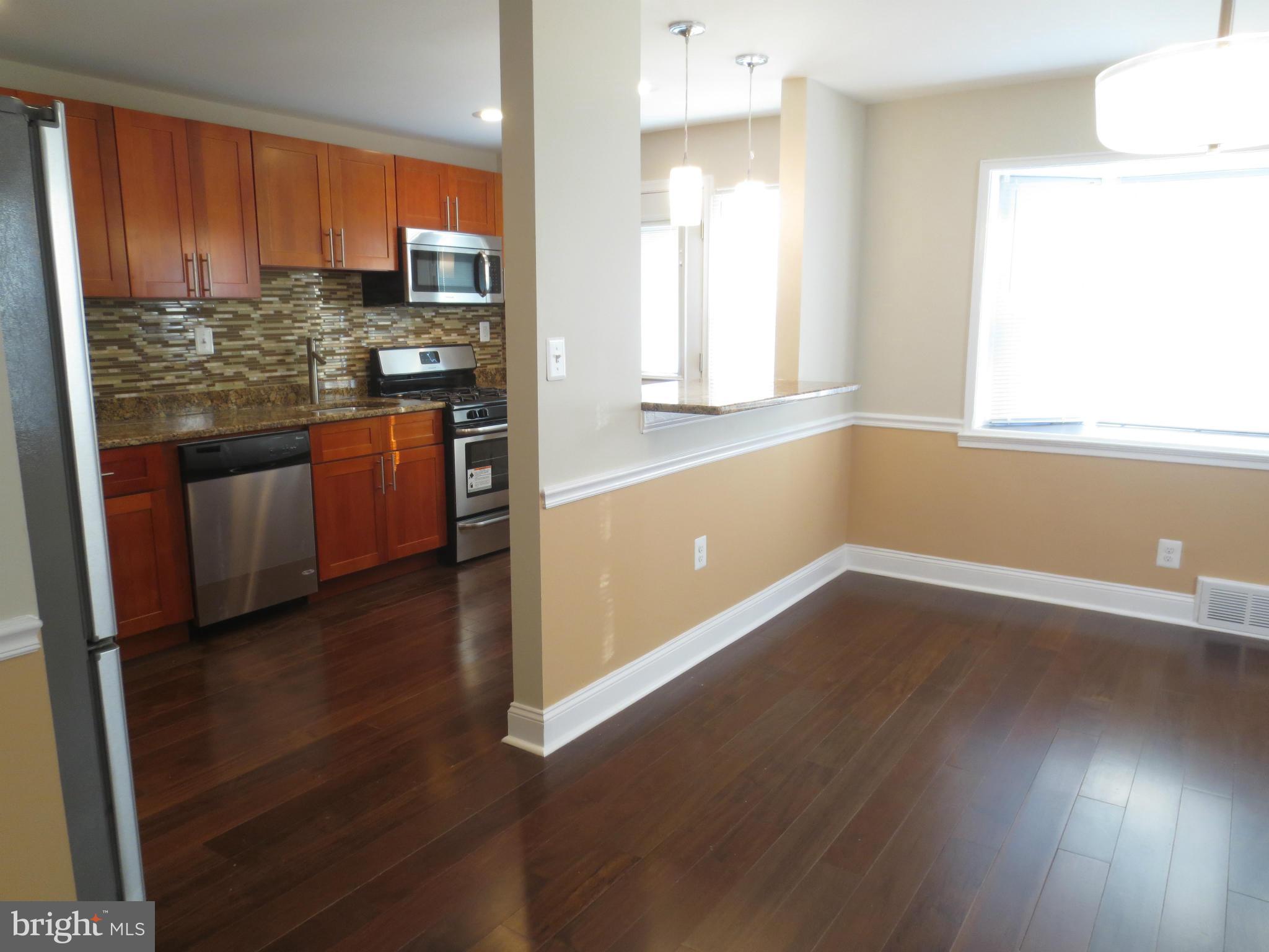 1801 Heathfield Road Baltimore, MD 21239 - Photo 6 of 28 a kitchen with stainless steel appliances wooden floors and wooden cabinets