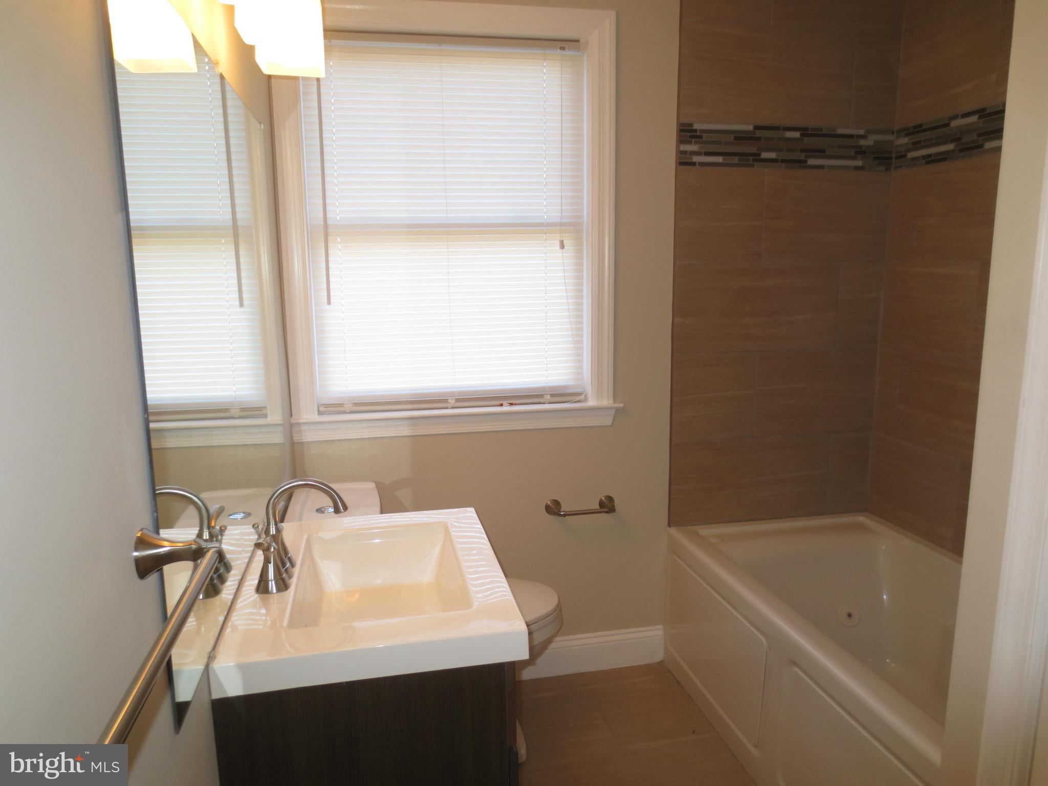 1801 Heathfield Road Baltimore, MD 21239 - Photo 10 of 28 a bathroom with a sink a mirror and a bathtub