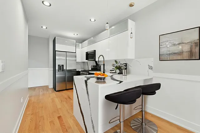 a kitchen with stainless steel appliances granite countertop a refrigerator a stove a sink dishwasher and white cabinets with wooden floor