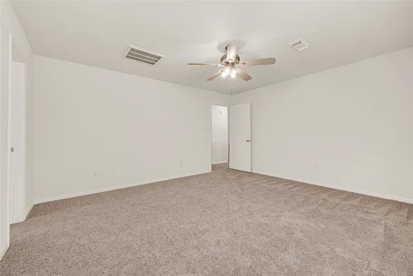 an empty room with a fan & a ceiling fan