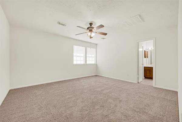 an empty room with windows and fan chandelier fan