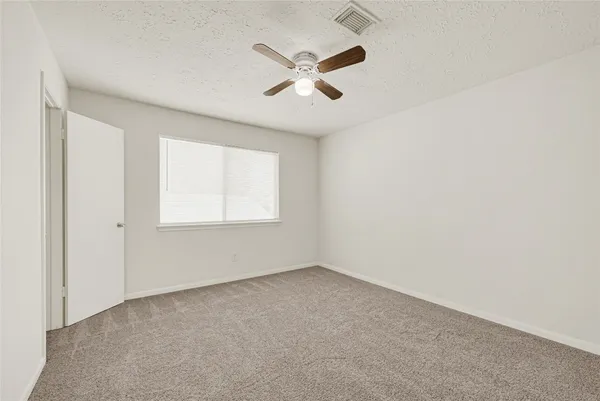 an empty room with a window and a ceiling fan