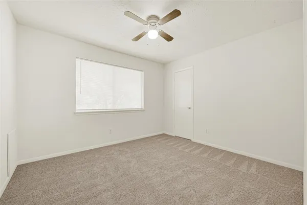 an empty room with a window and a fan