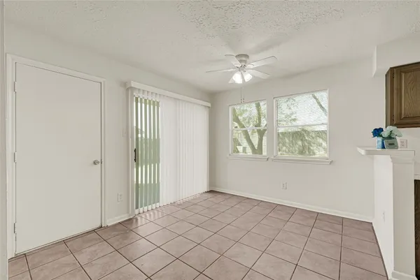 a view of an empty room with window and chandelier fan
