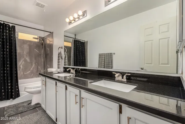 a bathroom with a double vanity sink toilet and a mirror