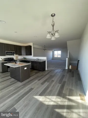 a kitchen with stainless steel appliances granite countertop a stove a sink dishwasher and a refrigerator with wooden floor