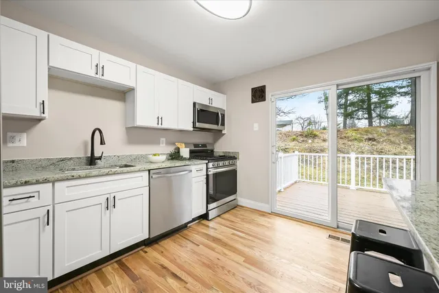a kitchen with granite countertop a stove a sink and a refrigerator