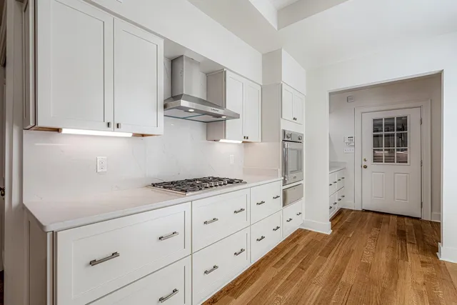a kitchen with white cabinets and wooden floor